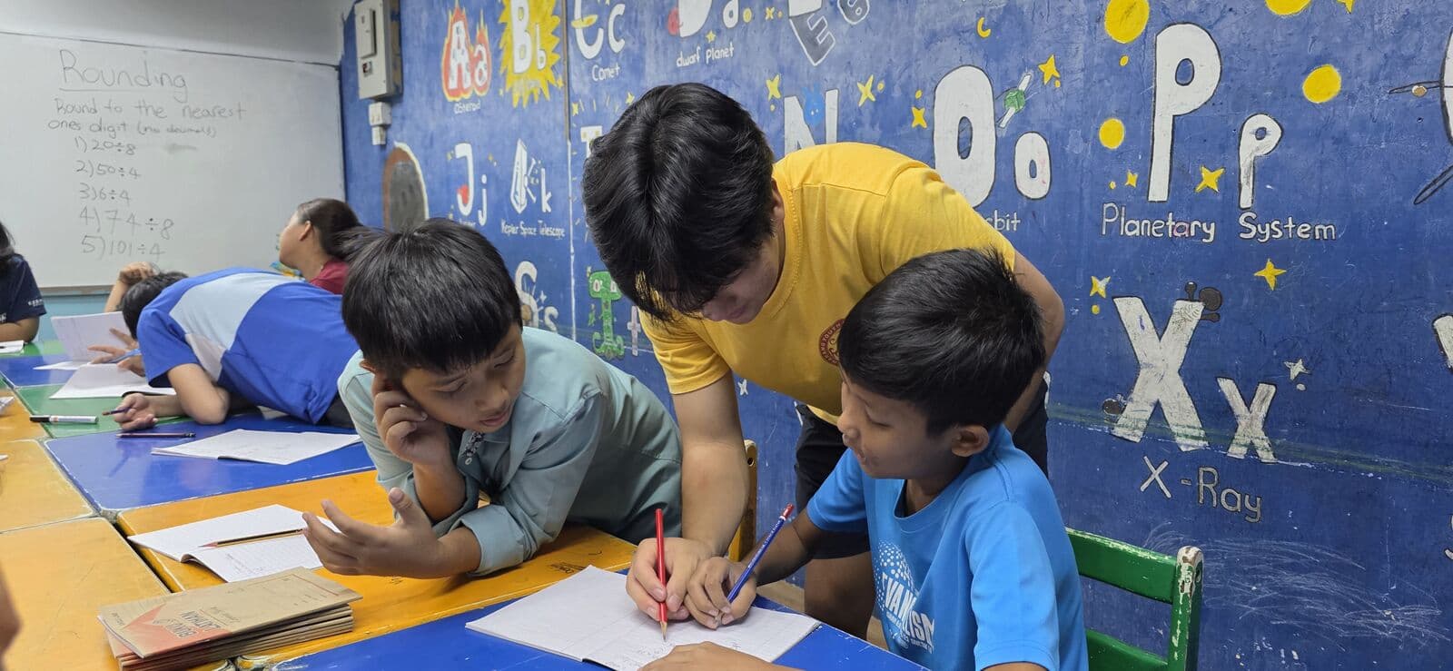 A Hwarang volunteer tutoring children in a classroom